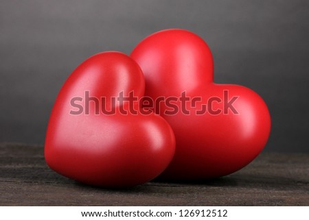 Two decorative red hearts on wooden table on grey background
