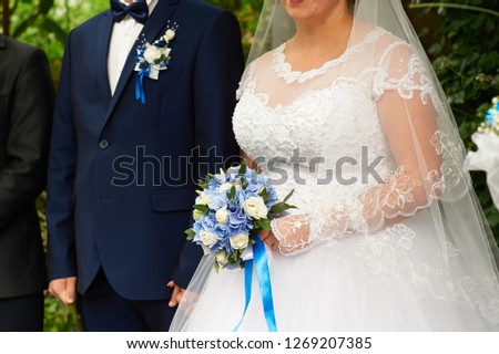 beautiful bridal bouquet of roses and hydrangeas on the background bride and groom stand at a wedding ceremony