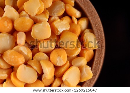 Yellow chopped peas in a barrel on a black background close up
