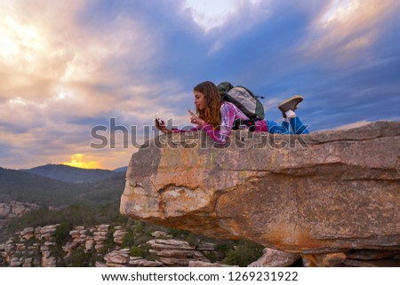 Hiker teen girl selfie smartphone on peak of mountain at sunset