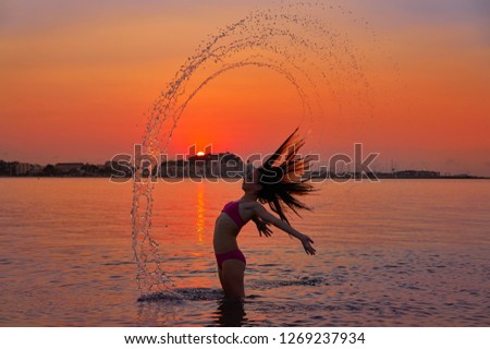 Girl flipping hair flip at sunset beach in orange sky