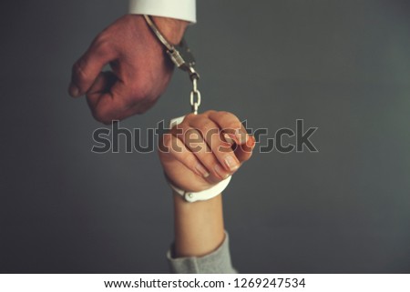 woman  and man hand handcuffs on dark background