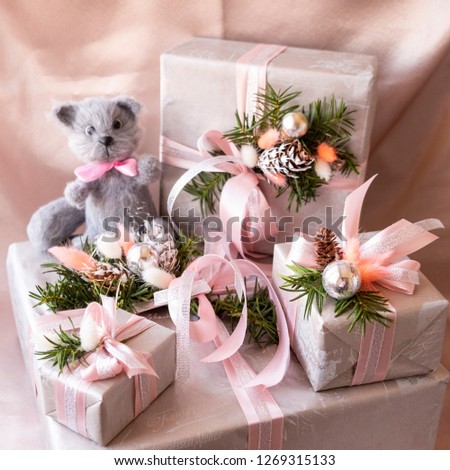 A group of beautifully decorated gifts with a toy - a gray cat on a bright background