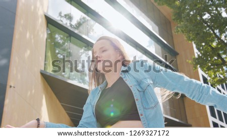 A young woman dancing outside. Medium shot. Lens flare