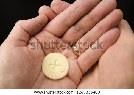 Cupped hands of a man holding a wafer of bread The Body of Christ when receiving communion at a Roman Catholic Mass Royalty-Free Stock Photo #1269336400
