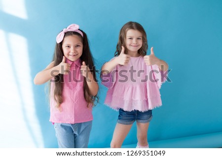 two little girl shows hands symbol thumb up