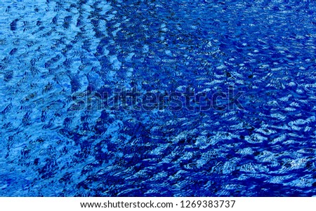 Close up photo of soft, deep blue swimming pool water that looks like aVan Gogh oil painting for background texture.