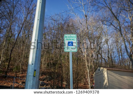 Handicap parking sign with trees in the background. 
