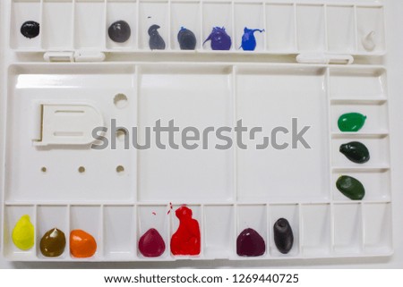 variety of watercolor colors that are prepared in a white dish.