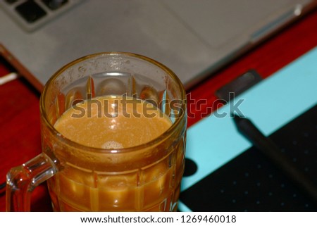 Hot coffee in cup with pen and computer on wood