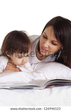 mother with her daughter lying on the bed with a book