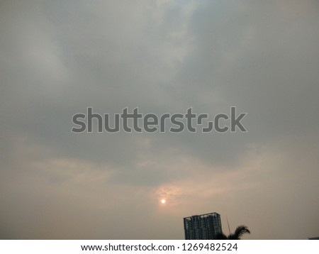 Sky view, sun moving to grey cloud over building, signal of raining
