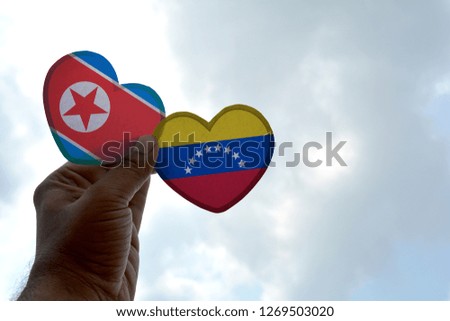 Hand holds a heart Shape North Korea and Venezuela flag, love between two countries