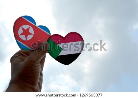 Hand holds a heart Shape North Korea and Sudan flag, love between two countries