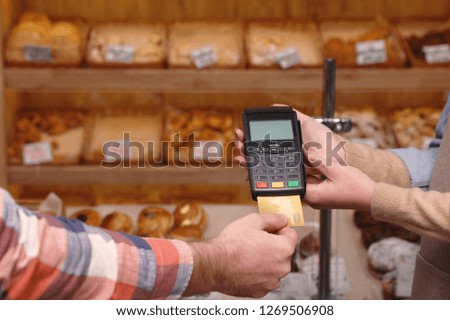 Man using bank terminal for credit card payment in bakery, closeup. Space for text