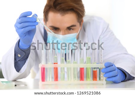 Male scientist working in laboratory, focus on rack with test tubes. Research and analysis