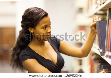 female african american college student looking for book in library