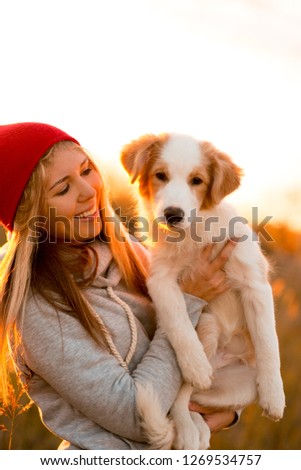 laugh girl with cool border collie dog puppy on hands in green field. sky sunset on background