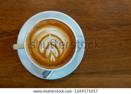close up white coffee cup and spoon with latte on wood table in the morning