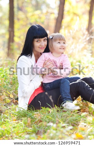 beautiful young mother and her daughter on the autumn forest