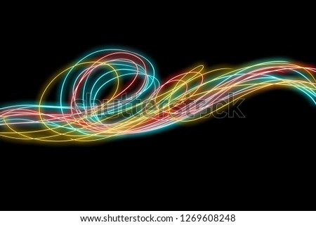 Long exposure effect, light painting effect. Neon  lines of color, curving and wavy lines isolated in black background.