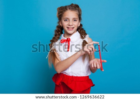 beautiful girl with braids with a red pencil on blue background 