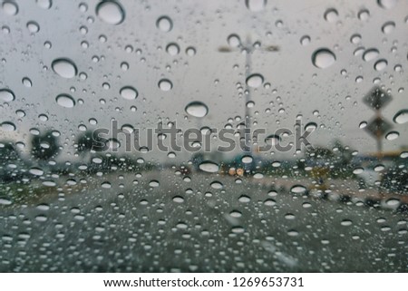 raining outside the car while driving , rainyday , raindrops on the car glass blur view