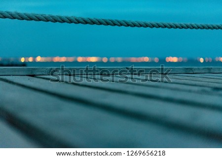 Bathing bridge with coastline and blurred lights in the background. Cold picture and bokeh.