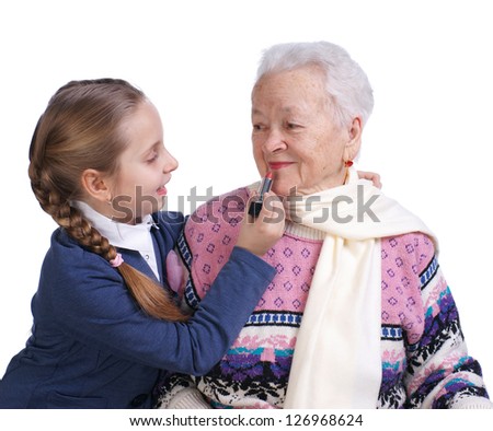 Pretty girl rouging grandmothers lips on a white background