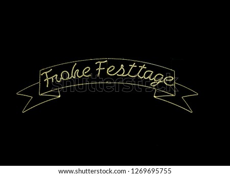 illuminated sign in the black night sky with the words "Frohe Festtage" meaning "Happy Holidays" written in German