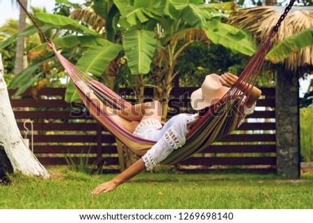 Beautiful woman sleeping in hammock. Happy beautiful woman in white dress relaxing in hammock. Beautiful woman in vacation. Vacation. Hammock. Tropical garden.