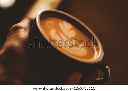 Cappuccino in white glass with wire drawing on milk froth.