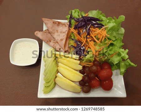 Fruits and vegetables salad and ham Served with salad dressing made from yogurt