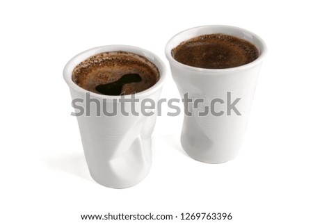Crumpled ceramic coffee cups as plastic one time cup isolated on white background. Funny white ceramic coffee cups.
