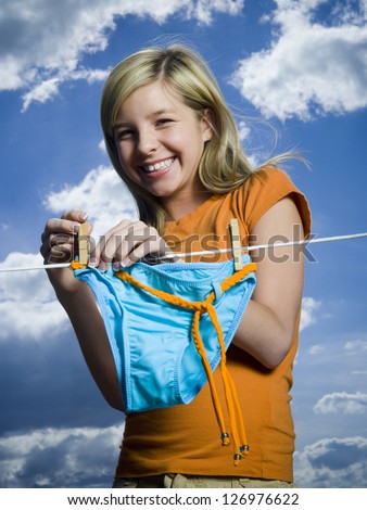 Portrait of a teenage girl drying a bikini bottom on a clothesline