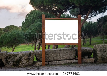 Front view of a wooden advertisement mockup at a green forest park. Park indications and regulations.