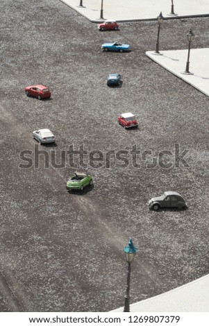 High angle shot over a miniature road with blue, red, green and white small cars under the sun.