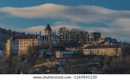 Castle and town Vimperk in cold sunny evening with blue sky and white clouds