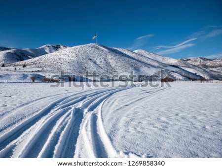 American Flag on a distant hill.  The flag stands out in stark detail against the blue sky and newly fallen snow.