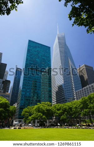 Bryant Park and skyscrapers of New York, Manhattan, on a sunny day of summer. Green grass lawn.