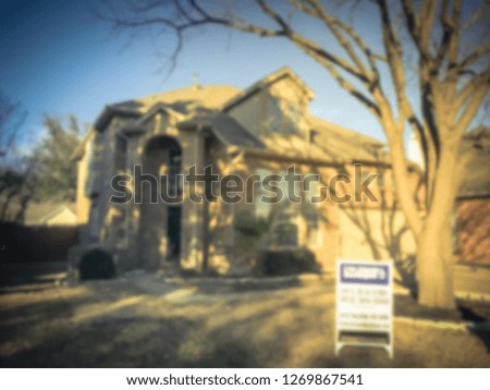 Abstract blurred front yard entrance of single family house with for sale yard sign