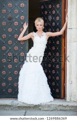 Woman in wedding dress standing near black door