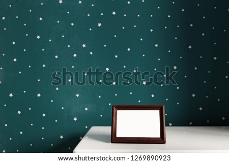 photo frame on the white table in dark green baby room