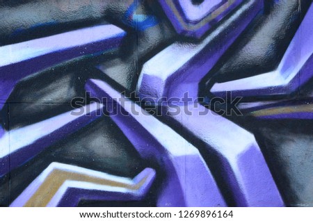 Fragment of graffiti drawings. The old wall decorated with paint stains in the style of street art culture. Colored background texture in purple tones