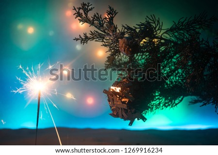 Christmas Decoration - bauble on branch of pine tree with holiday attributes on snow. Selective focus, bokeh background