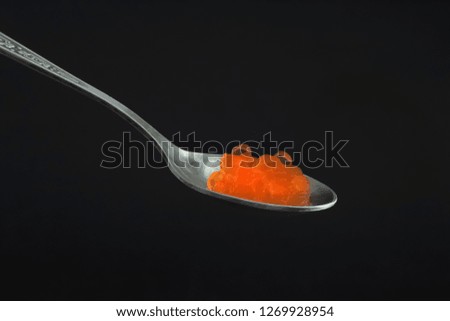 A photo red salmon caviar in an old vintage silver spoon on the dark background. Copyspace, place for text. Delicatessen and gourmet food. Selective soft focus. A photo of seafood