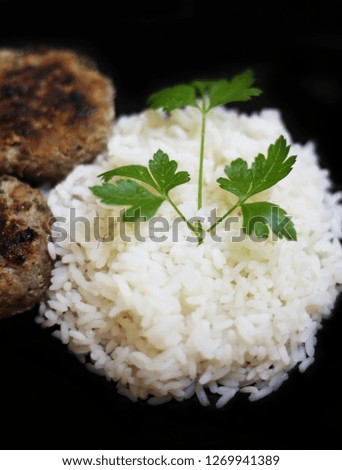 roasted burgers with rice and fresh wet parsley on black plate - food photography