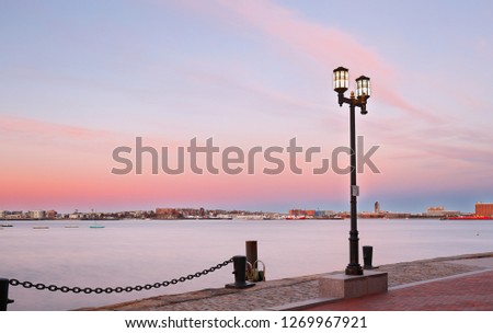 Boston Harbor after sunset. Photo shows Fan Pier Park brick sidewalk and Atlantic ocean . Boston Harbor is a natural harbor and estuary of Massachusetts Bay, located adjacent to city of Boston,MA.