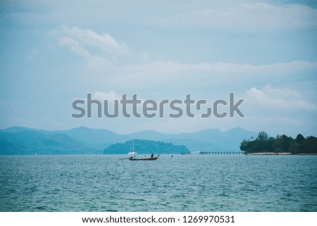 Amazing view of Fishing boat passing in front of Koh Naka Noi with beautiful seascape ocean horizon and blue sky at Phuket, Thailand in Summer season.