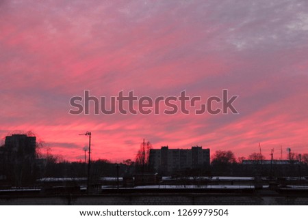 Red sunset above multistory house. Evening cityscape. City landscape. Dusk in town. Twilight with vermilion sunset. Big pink cloud above evening city